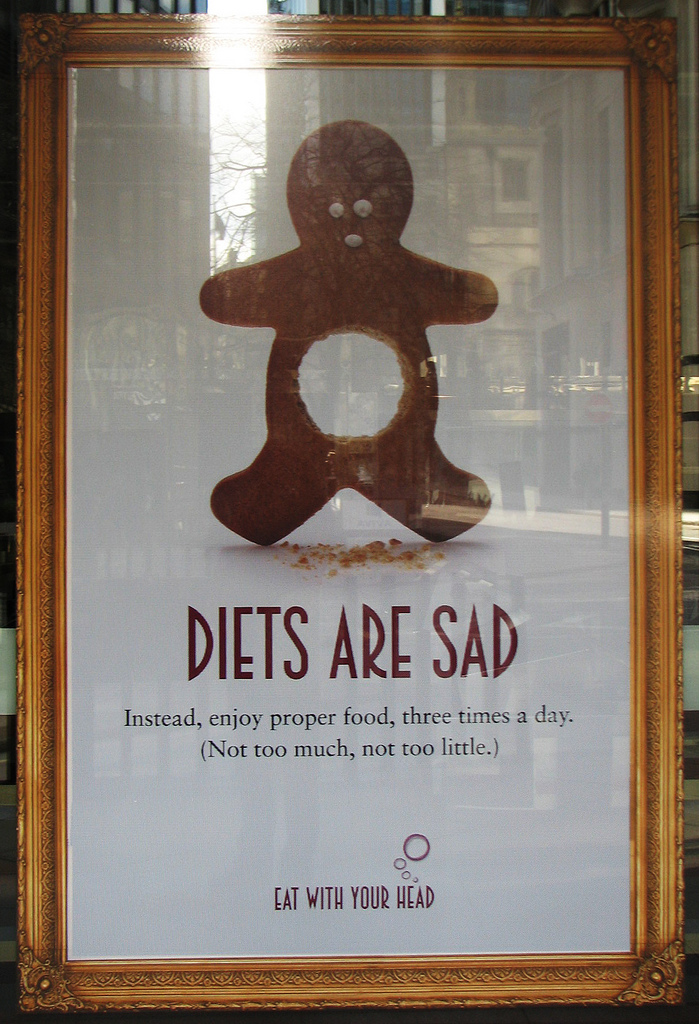 a gingerbread person with a hole punched out of the stomach area and text reading "Diets Are Sad. Instead, enjoy proper food, three times a day. (Not too much, not too little.) Eat with Your Head