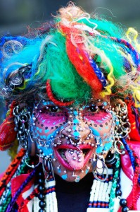 a very pierced-up woman with face paint and colorful hair