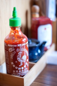 sriracha in front of a soy saue pot and ketchup bottle