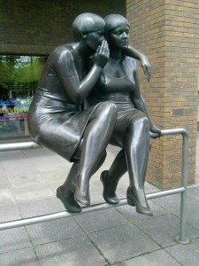 a statue depiction of someone whispering into someone else's ear