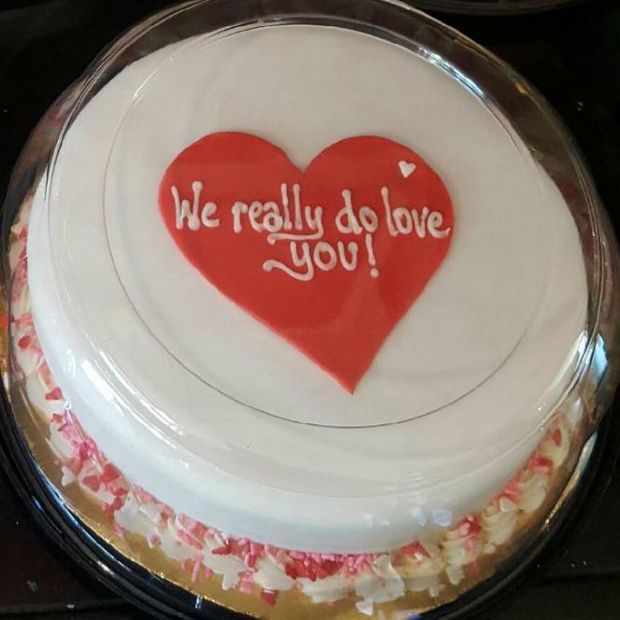 a white cake with a red heart and the text "we really do love you!" on it