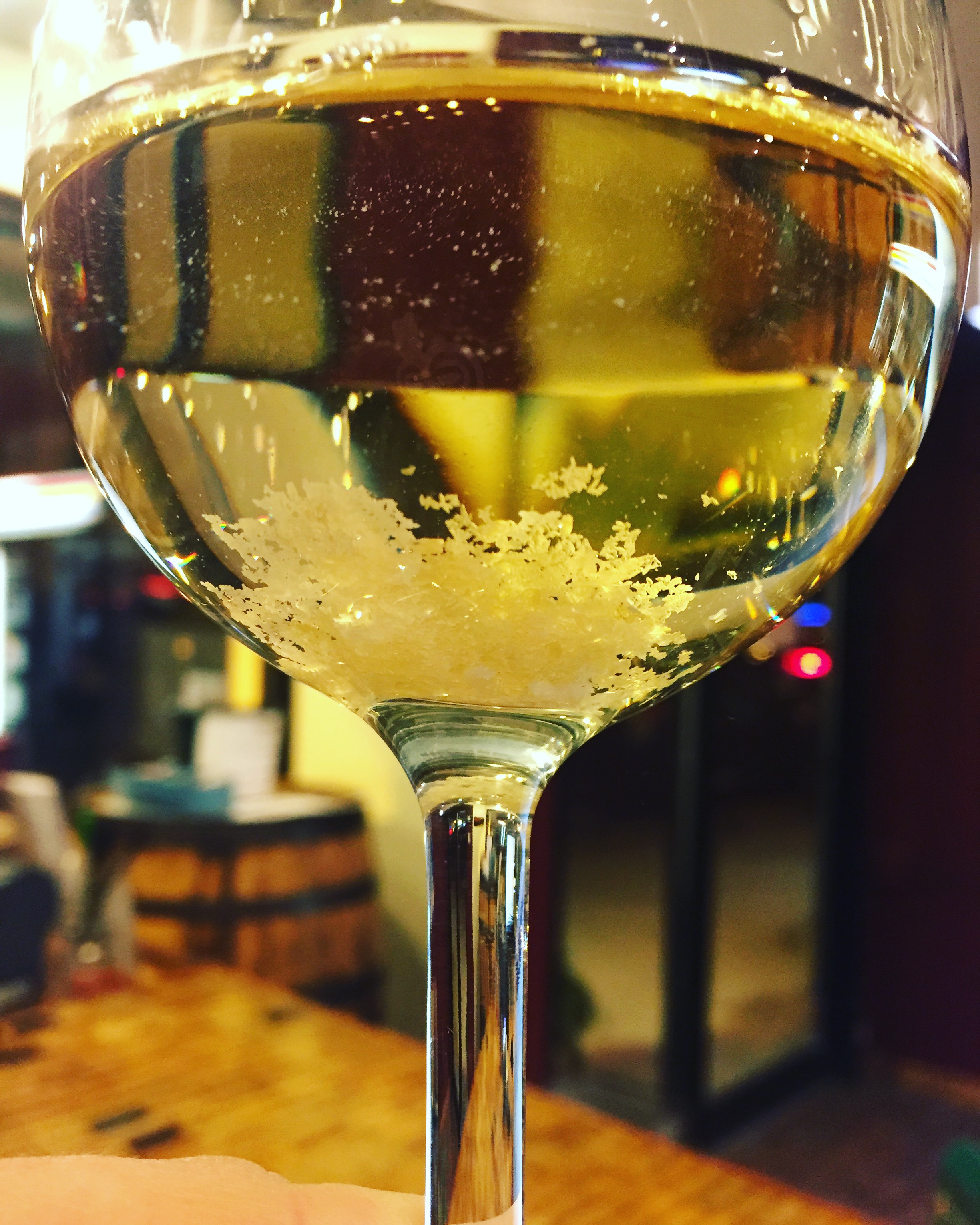 White wine with tartrate crystals in bottom of glass