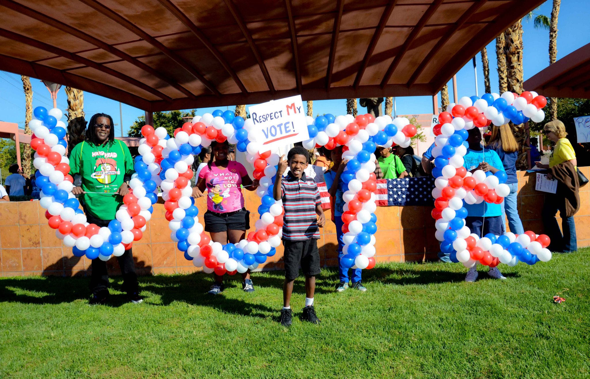 Giant balloons in the shape of "VOTE" and a child holding a sign that says "Respect my Vote"