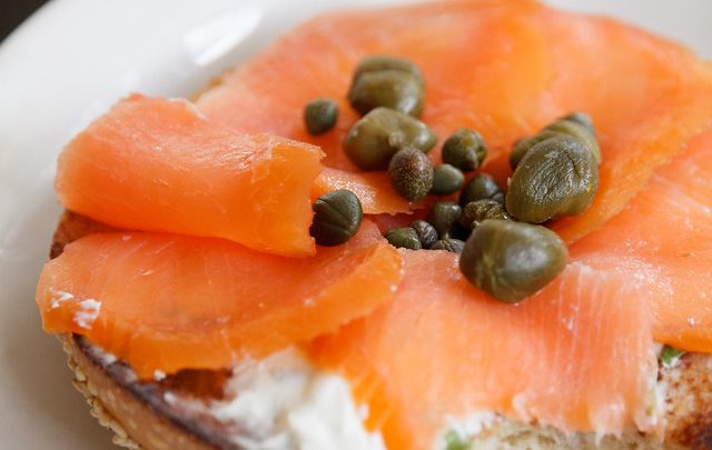 A photo of an open face bagel with lox and capers
