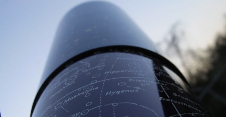 view looking down the side of a telescope with constellations printed on it
