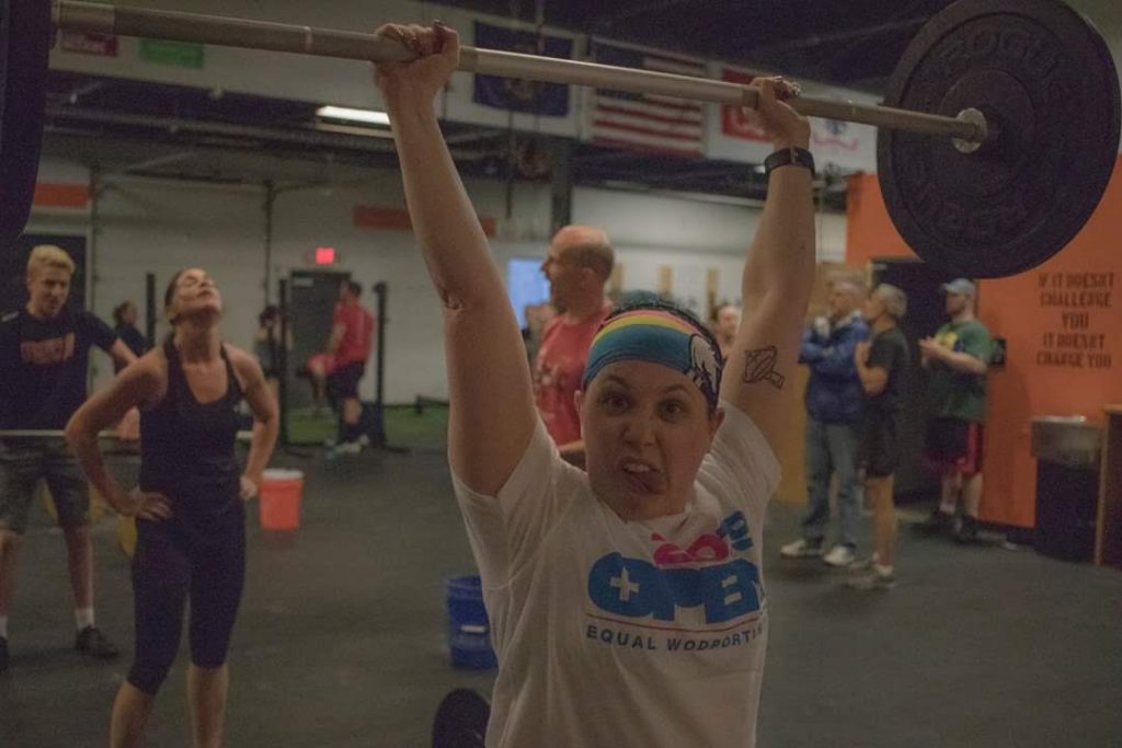 author holding barbell overhead making a silly face