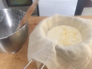 cultured butter separating in lined sieve