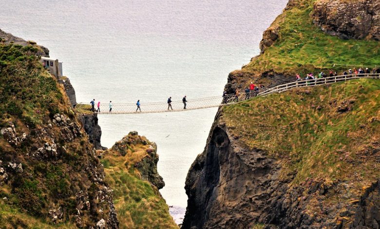 people walking on a thin bridge